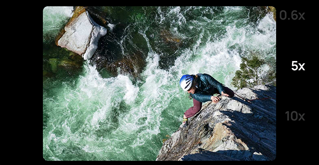 Zoom d'un homme sur une corde qui grimpe sur les rochers à côté d'une rivière qui coule. 